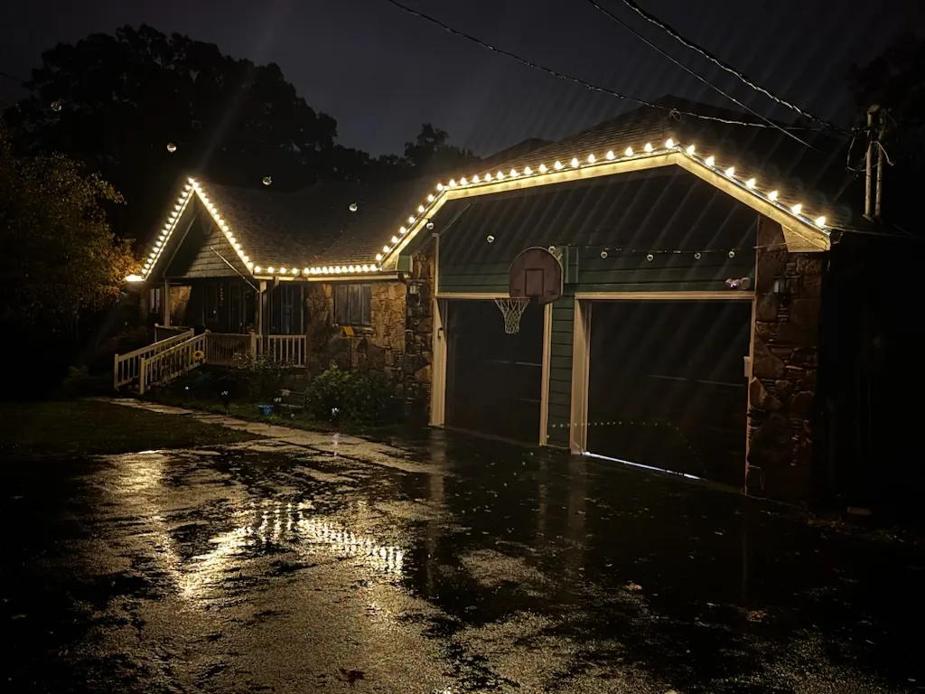 Warm white permanent lights tracing a garage roofline at night